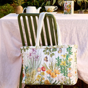 Floral-patterned tote bag on a chair with a table and teacups in the background