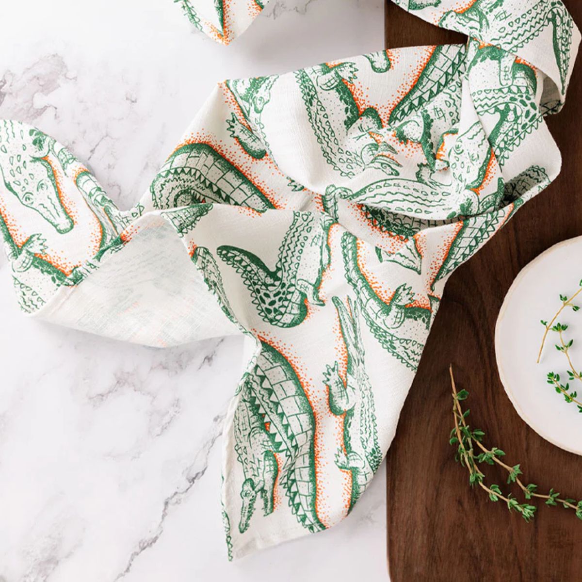 Green and orange crocodile patterned towel on a marble surface with a wooden background